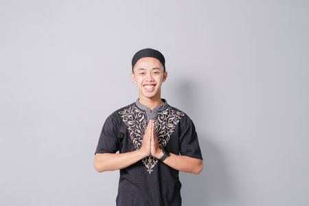 young asian muslim giving greeting, isolated on gray backgroundの写真素材