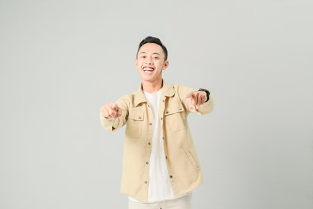young asian man pointing at something, isolated on gray backgroundの写真素材