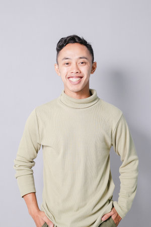 young asian man smiling confidently, isolated on gray backgroundの写真素材