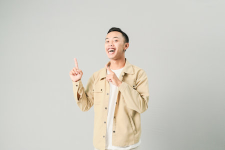 young asian man pointing at something, isolated on gray backgroundの写真素材