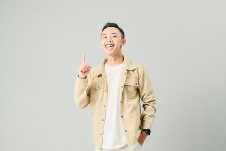 young asian man smiling confidently, isolated on gray backgroundの写真素材