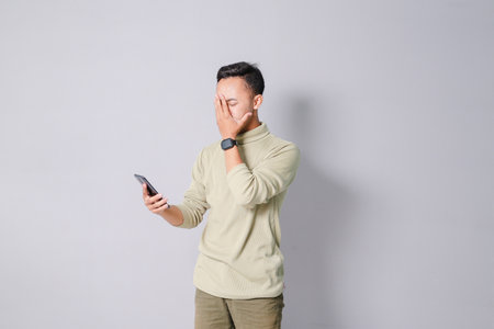 a young Asian is worried while looking at his smartphoneの写真素材