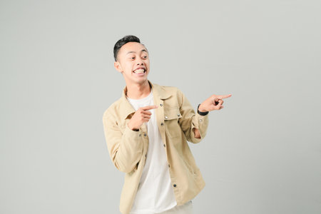 young asian man pointing at something, isolated on gray backgroundの写真素材