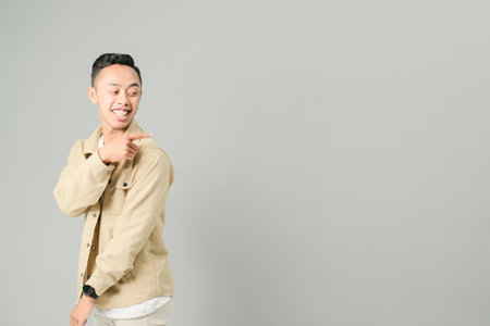 young asian man pointing at something, isolated on gray backgroundの写真素材
