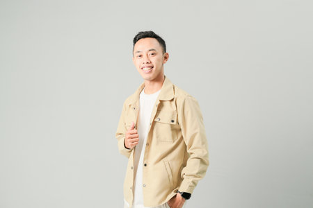 young asian man smiling confidently, isolated on gray backgroundの写真素材