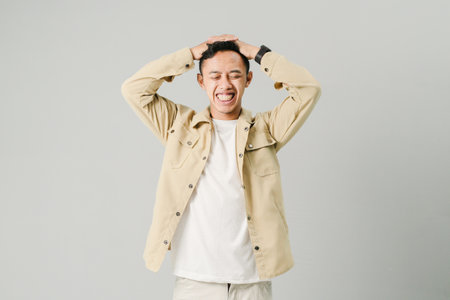 young asian man with disappointed expression, isolated on gray backgroundの写真素材