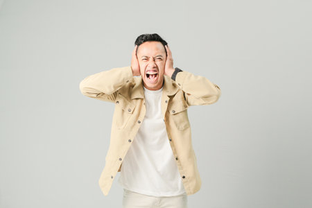 a young Asian man is covering his earsの写真素材