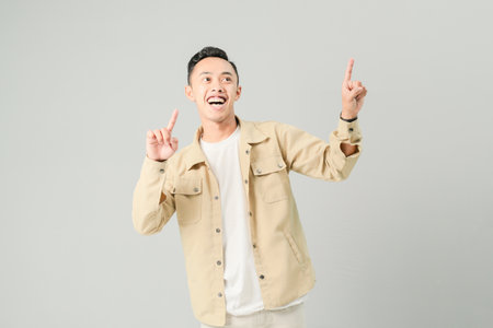 young asian man pointing at something, isolated on gray backgroundの写真素材