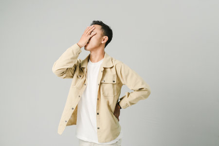 young asian man with disappointed expression, isolated on gray backgroundの写真素材