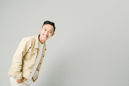 young asian man smiling confidently, isolated on gray backgroundの写真素材
