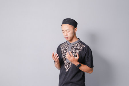 young asian muslim praying, isolated on gray backgroundの写真素材