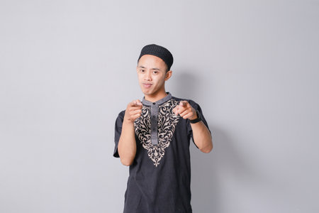 young asian muslim man pointing at something, isolated on gray backgroundの写真素材
