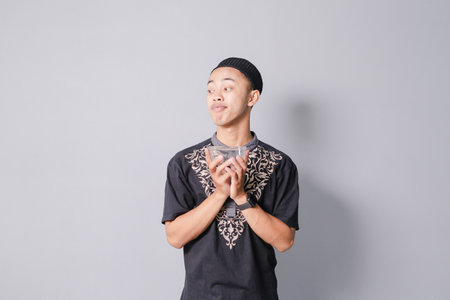 young asian muslim holding bowl, isolated on gray backgroundの写真素材