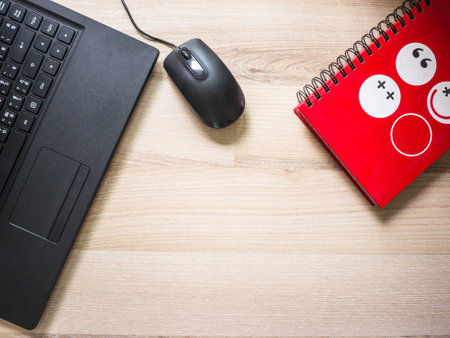 laptop and red notebook on the table on working day