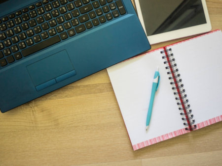 Office workplace with laptop, notebook, tablet and pen on wood tableの写真素材