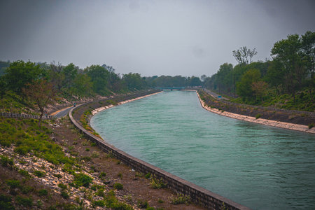 Long irrigation canal with flowing water surrounded by greenery and embankments, representing water...