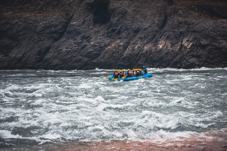 A group of adventure seekers enjoying white-water river rafting through strong rapids, surrounded by...