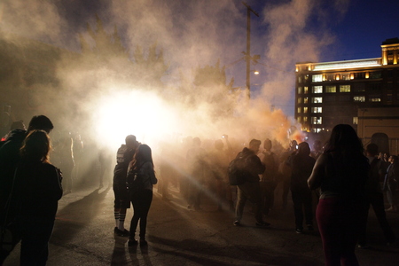 A crowd of people walk through a smoke bomb