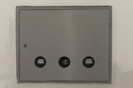 Closed electricity control box on white wall.の写真素材