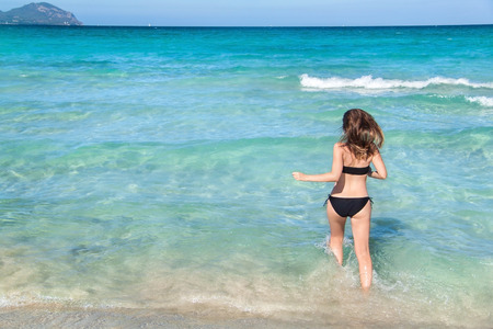 Young woman running into the water, Playa de Muro, Mallorca, Spain.の写真素材