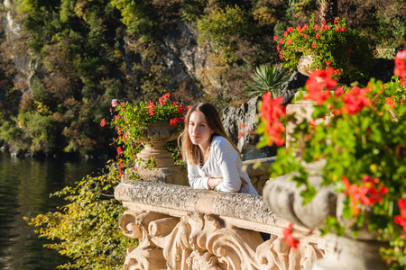 Young girl standing on the old terrace  balcony with flowers. Villa Balbianello. Lake Como, Italyの写真素材