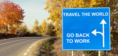 Travel the world or go back to work concept on road sign outdoors on a sunny autumn dayの写真素材