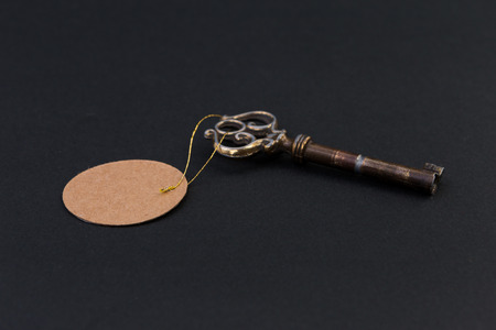 Old house key with blank tag or label on black backgroundの写真素材