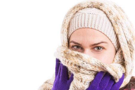 Woman wearing warm clothes covering her mouth with knitted scarf isolated on white background with...