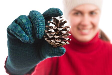 Happy smiling woman holding a pine cone wearing hat and gloves as joyful winter holidays conceptの写真素材