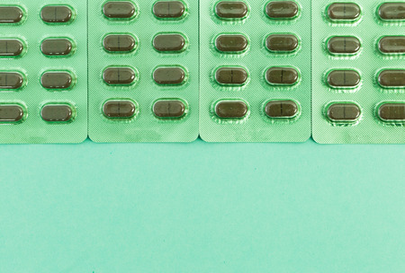 Green capsules on blisters and bottom copyspace as natural homeopathic healtcare concept