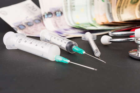 Syringes and many paper money banknotes as healthcare and pharmaceutical industry conceptの写真素材