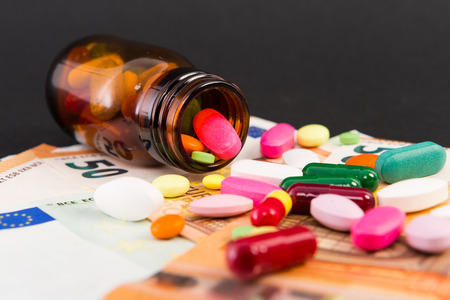 Spilled pills on euro banknotes as pharmacy investment conceptの写真素材