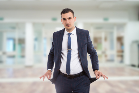 Broke real estate agent or realtor pulling empty pokets inside out as bankrupcy or poverty concept on lobby backgroundの写真素材