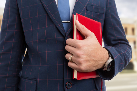 Close-up of real estate agent or realtor holding red agenda notebook as business conceptの写真素材