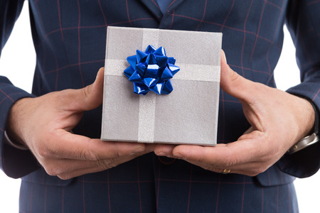 Close-up of elegant lover or boyfriend hands holding silver gift box as romantic present concept isolated on white backgroundの写真素材
