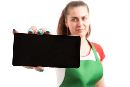 Young woman supermarket or retail worker showing empty blank smartphone display as screen text area concept isolated on white backgroundの写真素材