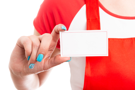 Empty blank business card concept with female supermarket or retail employee hand close-up and red apron uniform isolated on white backgroundの写真素材