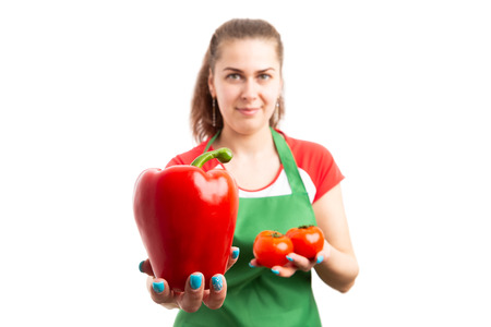 Young woman retail or store employee holding red pepper and tomatoes as fresh supermarket vegetables advertising concept isolated on white backgroundの写真素材