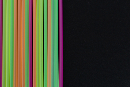 Lined up bright colorful plastic straws decorative art design as bar drink beverage single use product concept isolated on black backgroundの写真素材
