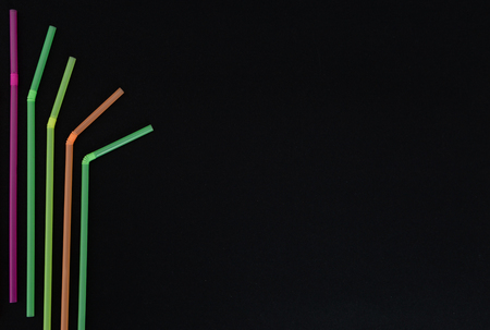 Single use harmful plastic waste ban concept with colorful straws bent artistic design pattern isolated on black backgroundの写真素材