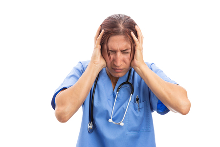 Stressed female hospital nurse grabbing head because of pain as overworked clinic medic headache concept isolated on white backgroundの写真素材