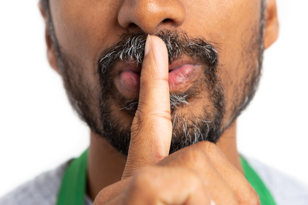 Close-up silence gesture with index finger on mouth made by hypermarket or supermarket employee...