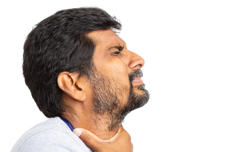 Close-up of indian man having a sore throat and touching neck with one hand isolated on white studio...