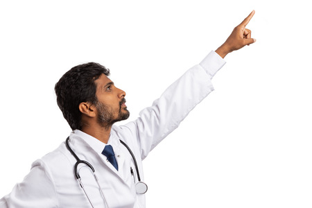 Side-view of indian male medic pointing up with index finger at blank copy text area for advertising isolated on white backgroundの写真素材