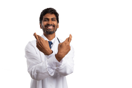 Friendly medic crossing fingers at both hands as good luck gesture isolated on white studio backgroundの写真素材