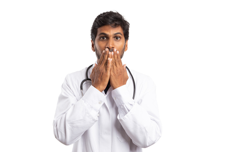 Indian man medic using palms to cover mouth as unexpected secret concept isolated on white backgroundの写真素材