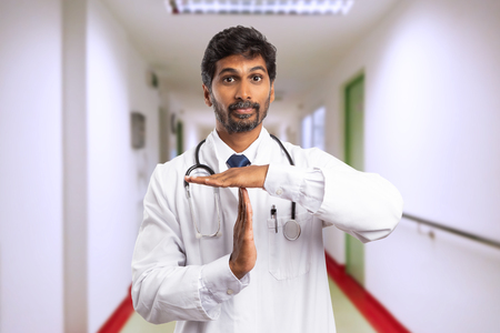 Indian doctor man or medic with serious expression making time out gesture using palms as break concept in hospitalの写真素材