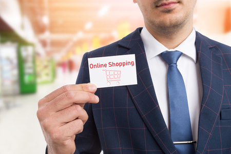 Man wearing suit and tie holding online shopping white business card in hand as digital commerce conceptの写真素材