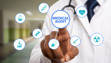 Indian male medic touching medical audit text circle button on close-up futuristic display with healthcare symbolsの写真素材