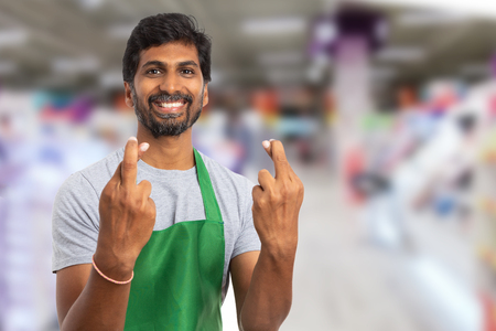 Hypermarket or supermarket male indian employee holding fingers crossed at both hands with trustworthy expression as good luck gestureの写真素材